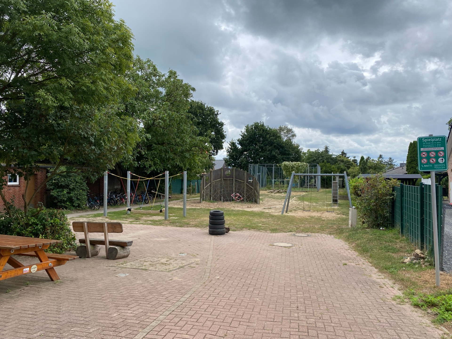 Spielplatz hinter der Schule mit Klettergerüst, Schaukel und Fahrradständern